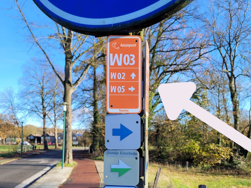 Een oranje bordje op een keuzepunt geeft aan in welke richting het volgende keuzepunt ligt.