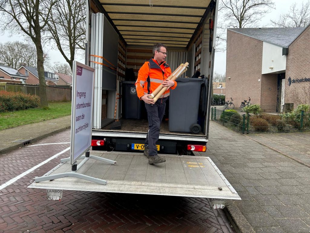 Buitendienstmedewerkers brengen de materialen het stembureau in.