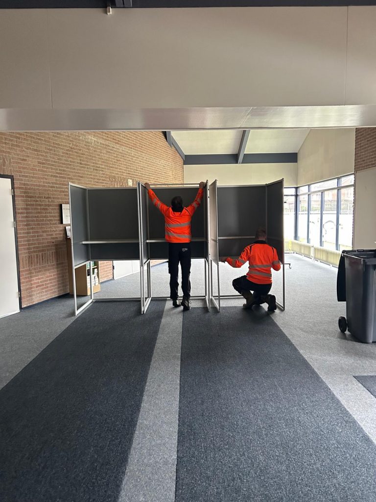Buitendienstmedewerkers plaatsen de stemhokjes in het stembureau.