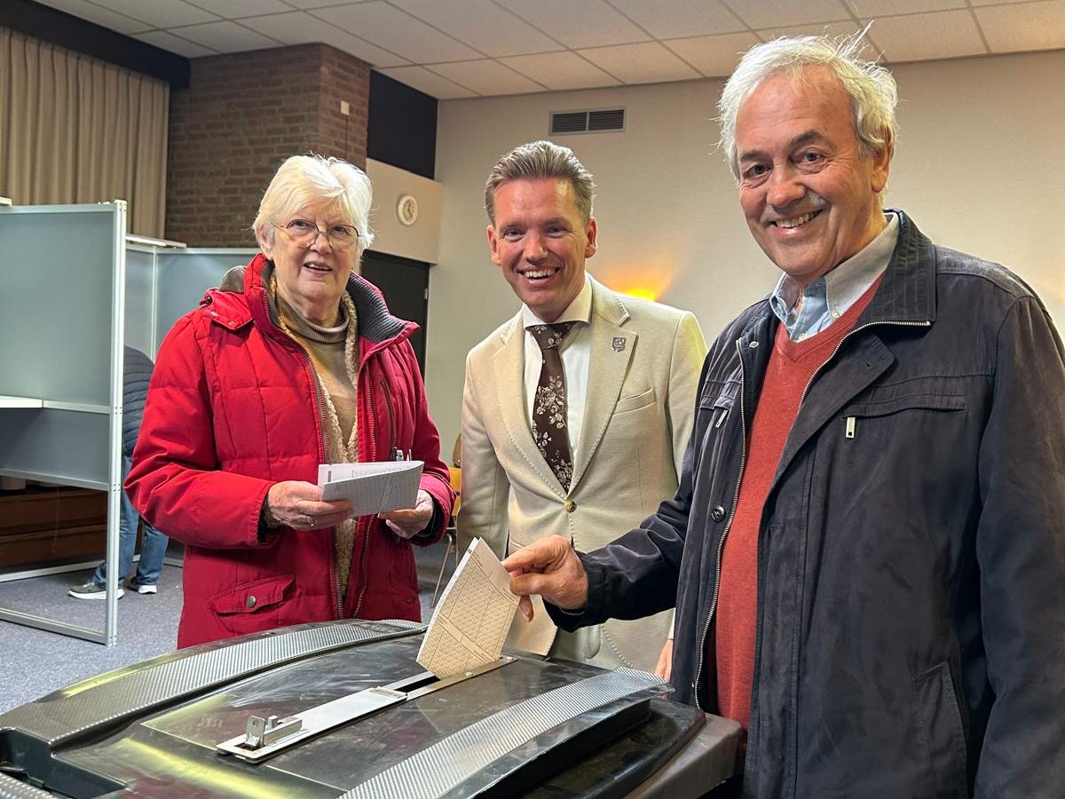 Burgemeester met enthousiaste inwoners die komen stemmen